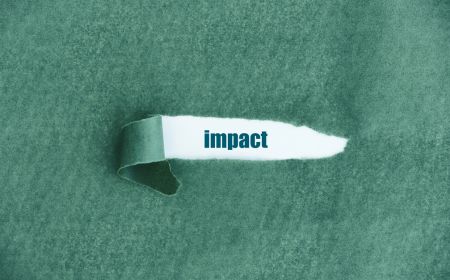 A decorative tear on green paper revealing the word impact